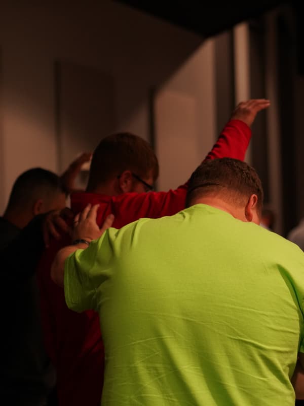 Men praying for each other while worshipping Jesus