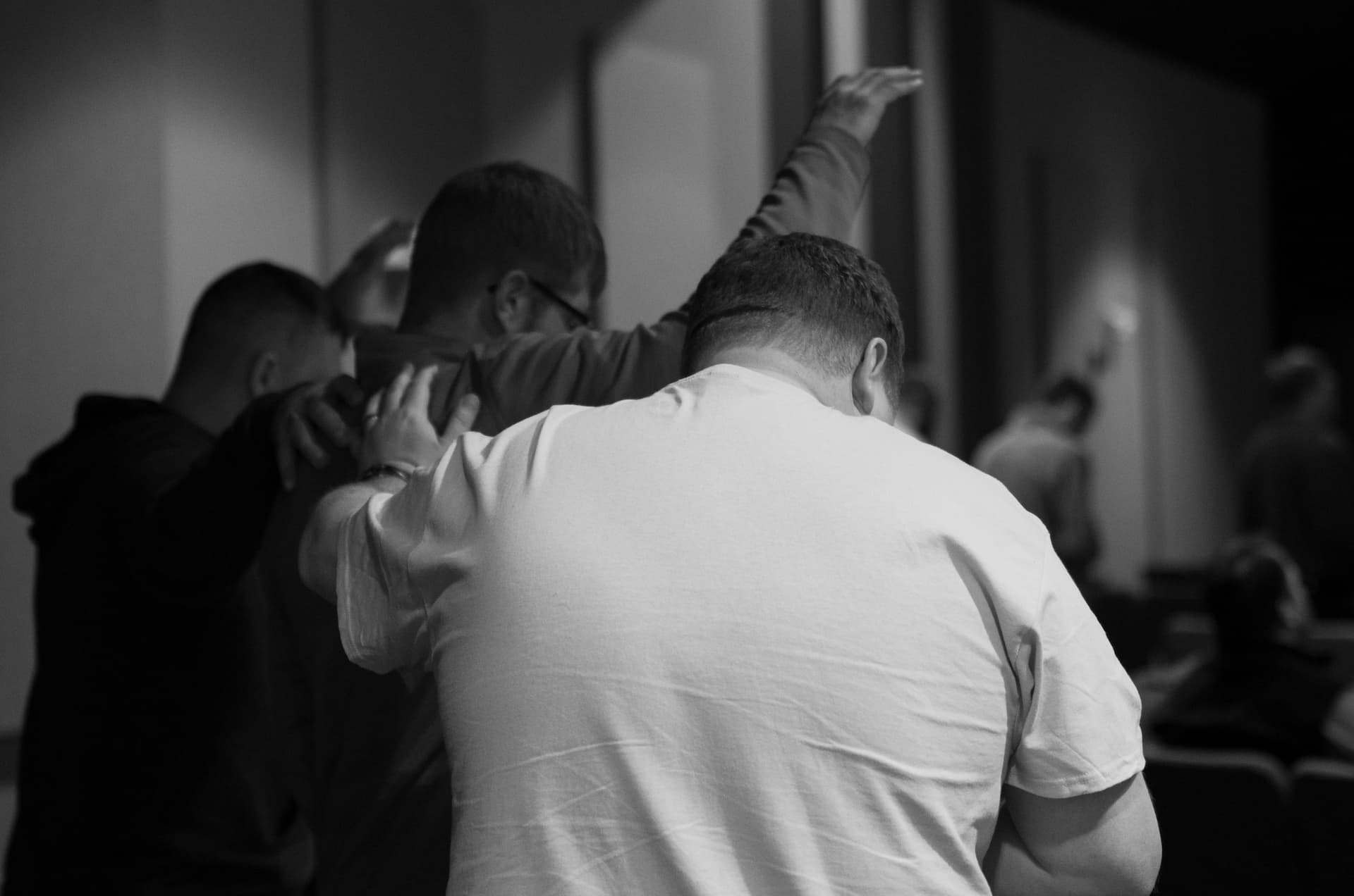 Men praying for each other while worshipping Jesus